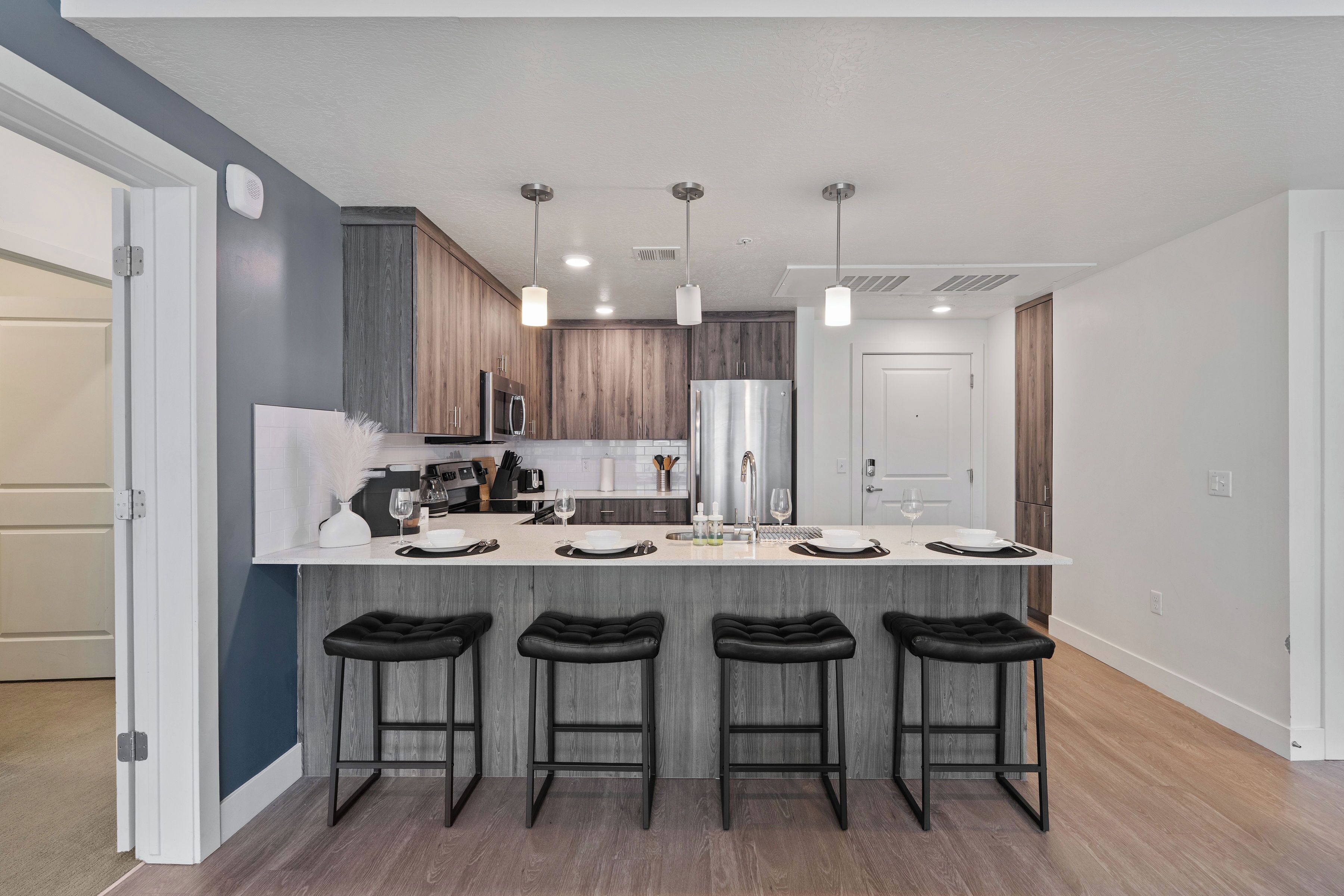 A modern kitchen with a central island, bar stools, and pendant lighting.