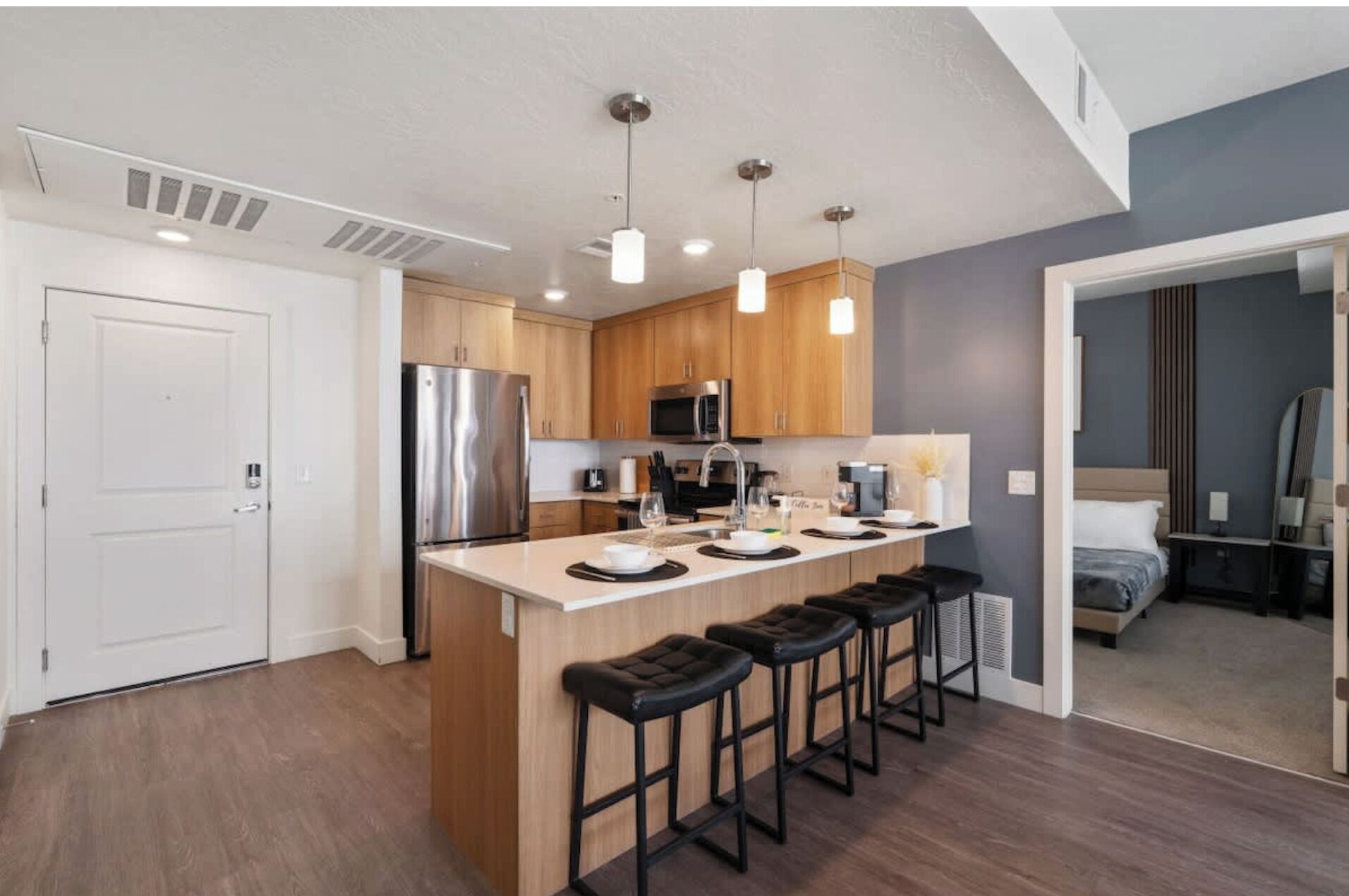 A modern kitchen with a central island, stainless steel appliances, and bar stools.