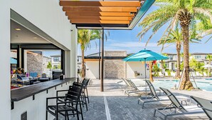A poolside area with lounge chairs, a bar, and a pool. - Modern Getaway w/Game Room + Pvt Pool + BBQ Near Universal and I-Drive (Orlando)