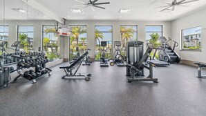 A modern gym with various exercise equipment, large windows, and a view of palm trees and buildings. - Modern Getaway w/Game Room + Pvt Pool + BBQ Near Universal and I-Drive (Orlando)
