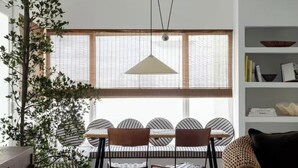 A dining area with a table and chairs, a hanging light fixture, and a large window with blinds. - 2 Bedroom Steps 2 Sand Oceanview Beach Retreat (Marina del Rey)