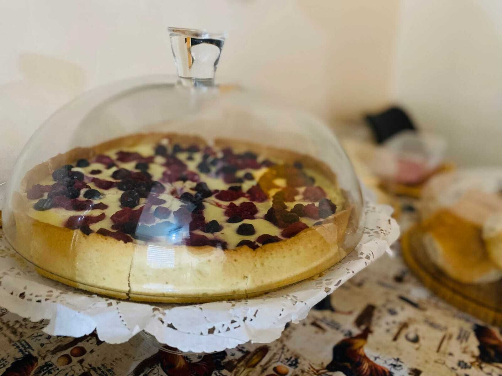 Uma sobremesa coberta por uma cúpula de vidro, colocada sobre um sousplat de renda.