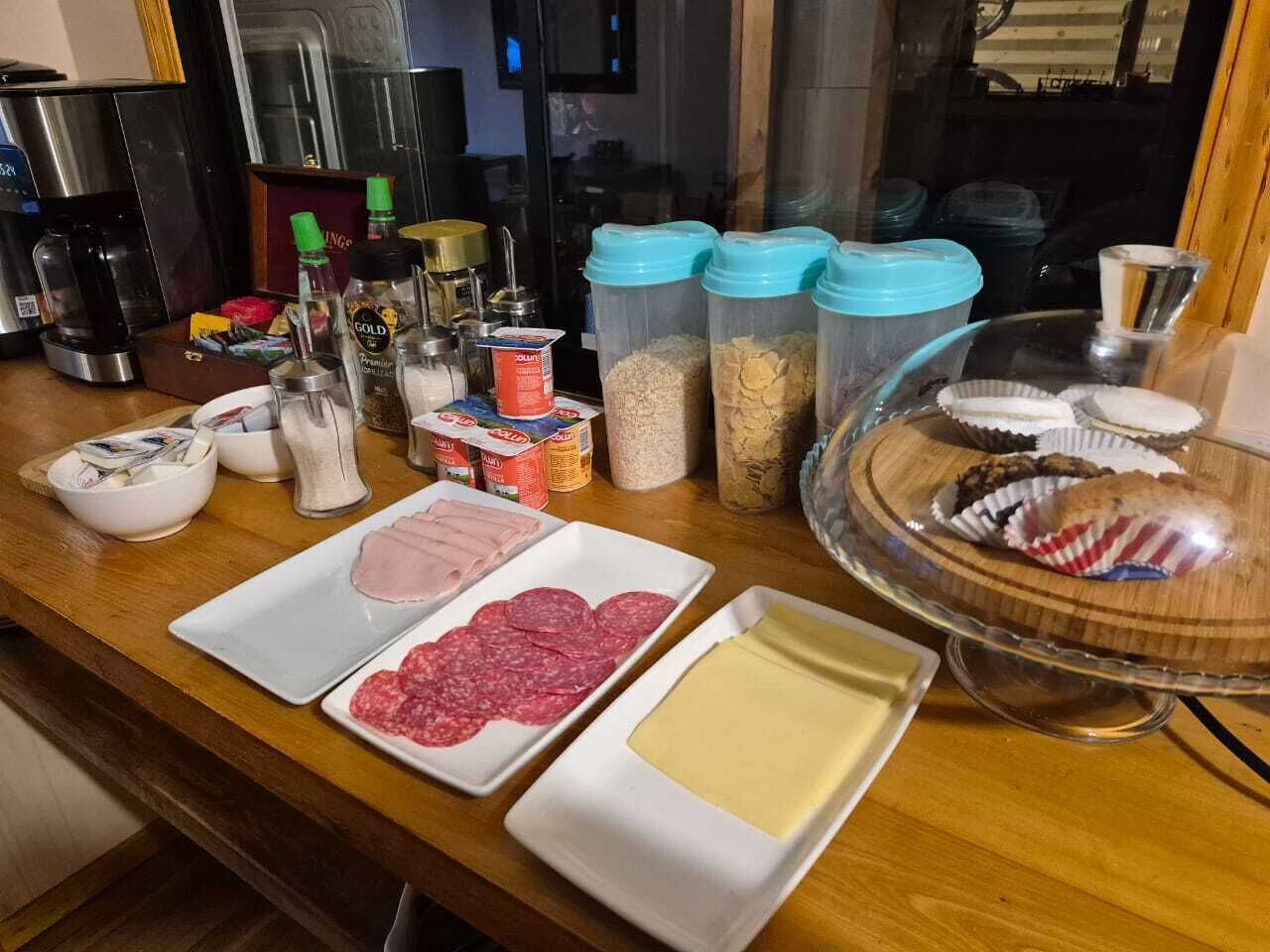 A kitchen counter with various food items and condiments, including sliced meats, cheese, and containers of spices.