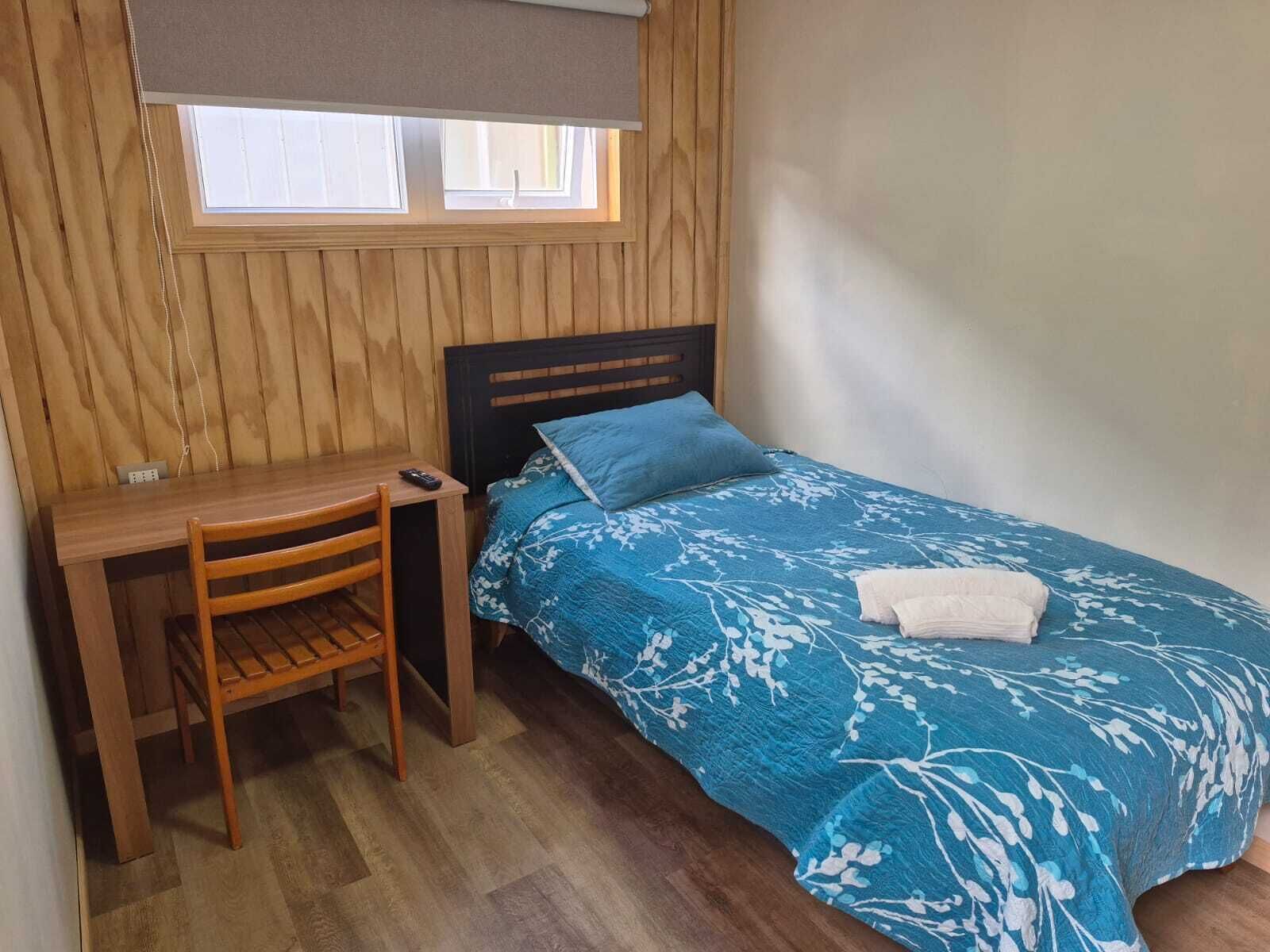 A room with a bed, a desk, and a chair.