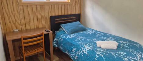 A room with a bed, a desk, and a chair.