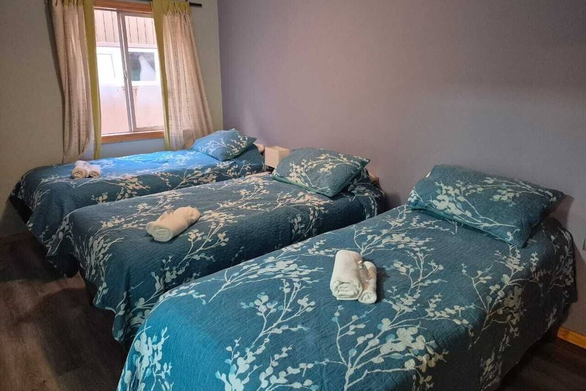 Una habitación con tres camas, cada una con una colcha de motivos florales y una toalla enrollada sobre la cama.