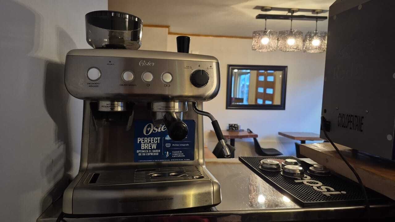 Una máquina de café espresso comercial con una etiqueta que dice 'Perfect Brew' en un ambiente de cafetería.