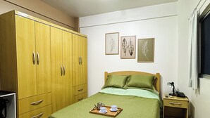 Un dormitorio con una cama, un armario, una mesita de noche y un ventilador de techo.