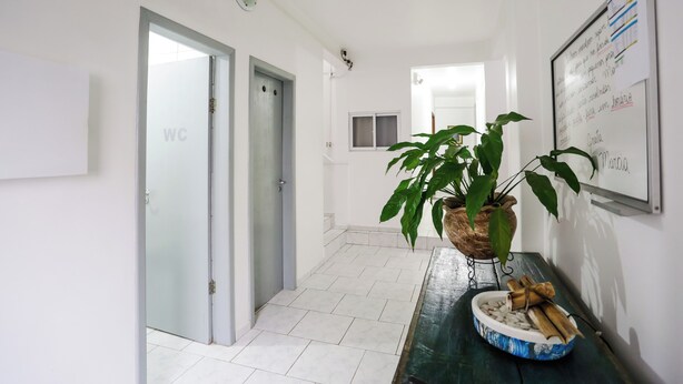Un couloir avec des toilettes, une plante en pot, un tableau blanc et une table en bois sur laquelle se trouve un bol.
