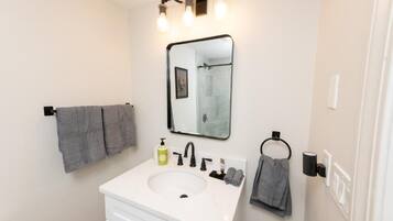 A bathroom with a white sink, black faucet, and a mirror with lights above it.