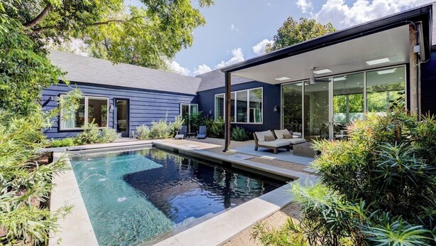 Ett modernt hus med en swimmingpool, utomhusmöbler och en täckt uteplats.