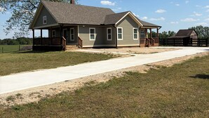 A two-story house with a porch, a driveway, and a large tree in the background. -  Deer Sanctuary Pasture Views & Total Relaxation (Statham)