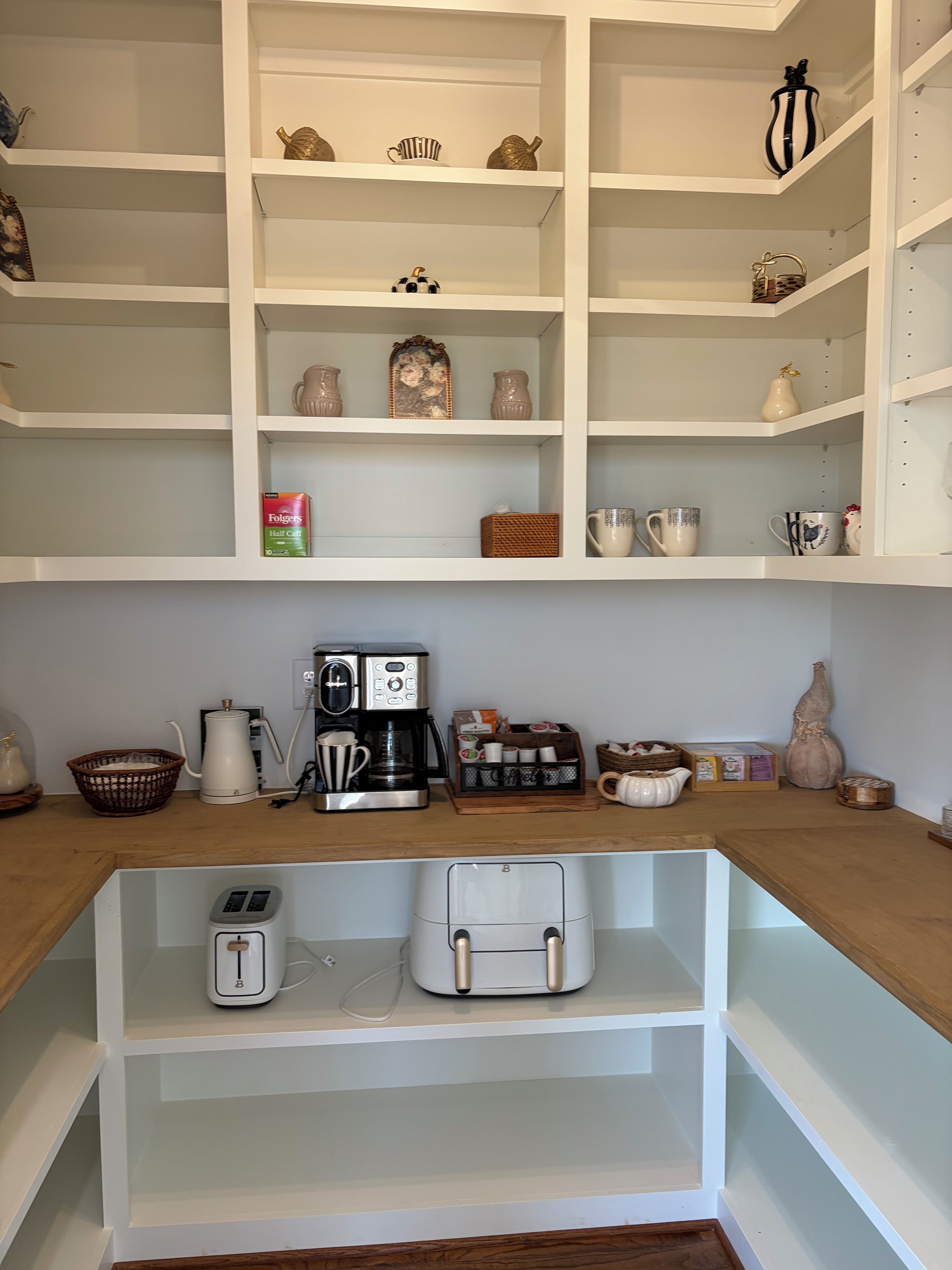 Une cuisine avec des étagères blanches, une machine à café, un grille-pain et divers ustensiles de cuisine.