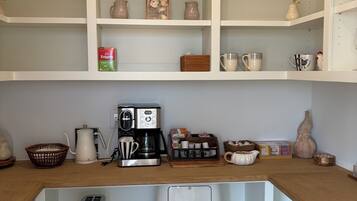 Une cuisine avec des étagères blanches, une machine à café, un grille-pain et divers ustensiles de cuisine.