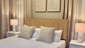 Un dormitorio con cama, mesitas de noche, ventilador de techo y cortinas.