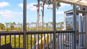 A covered outdoor area with a view of trees and a building. - Barrier Dunes 130 - 152 Millie's Dream (Port St. Joe)