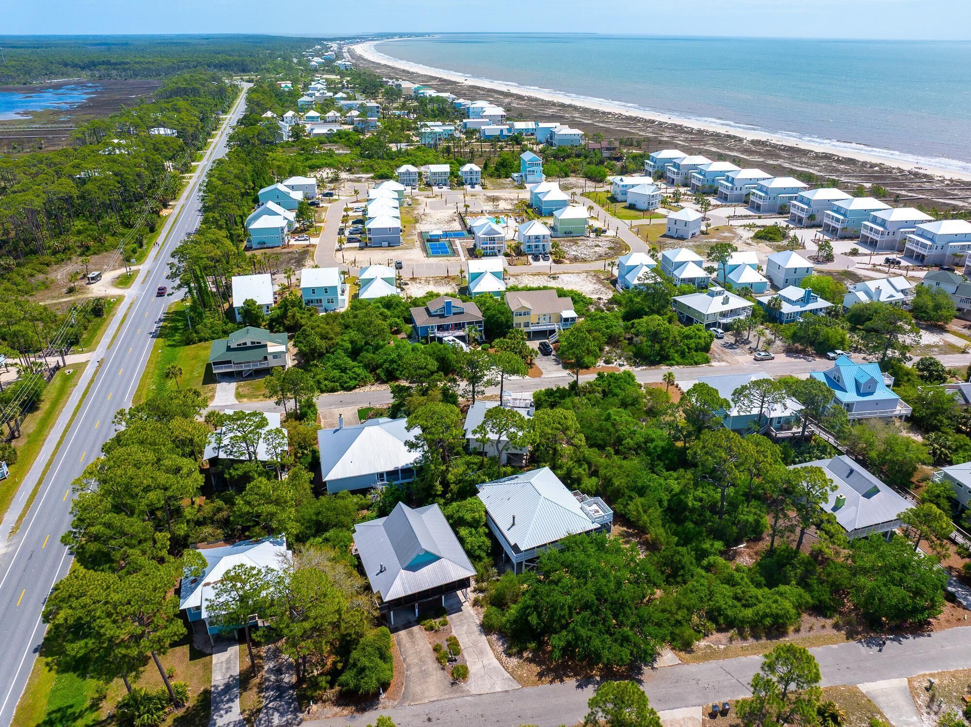 Vista aérea de una zona residencial costera con casas, una carretera y una playa.