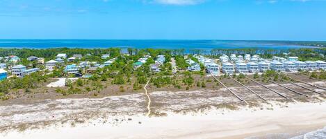 Un resort costero con propiedades frente a la playa, una playa de arena y una vista despejada del océano.