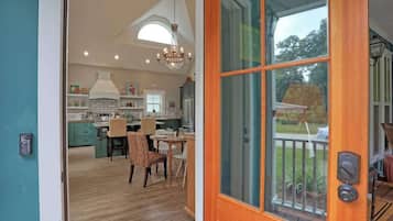 Une cuisine moderne avec un lustre, un plancher en bois et un coin repas avec des chaises.
