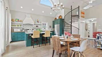 Une cuisine spacieuse avec des meubles de couleur turquoise, un îlot central et un lustre.