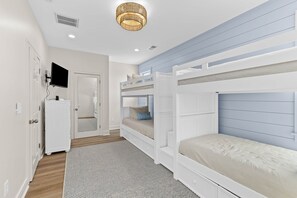 Une chambre avec des lits superposés, une télévision, une armoire et une porte.