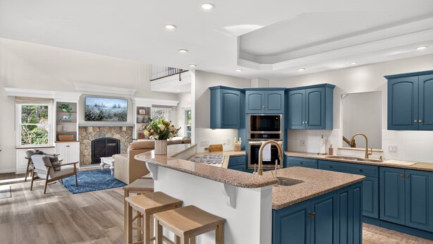 Una cocina moderna con armarios azules, una isla central y una chimenea de piedra.