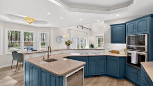Una cocina moderna con armarios azules, encimeras de granito y una isla grande.