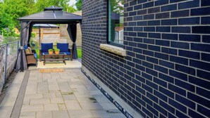 Un'area patio coperta con un angolo salotto, una pergola e un muro in mattoni.
