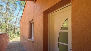 Un edificio con fachada texturizada, una puerta con paneles de vidrio esmerilado y una ventana.