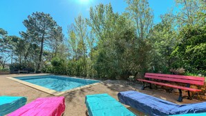 Un área de piscina con sillones de descanso y una banca.