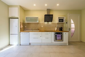 A modern kitchen with a refrigerator, microwave, oven, and dishwasher. - Chez Marion - Climatisation - Piscine (Maubec)