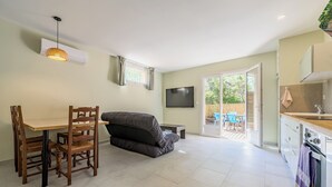 Una sala de estar moderna con sofá, mesa de comedor, sillas, televisor y una zona de cocina con estufa.