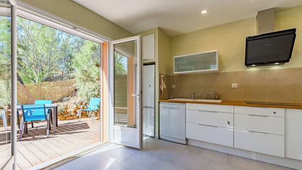 Una cocina moderna con un suelo de vidrio corredizo que da a un área de estar exterior.