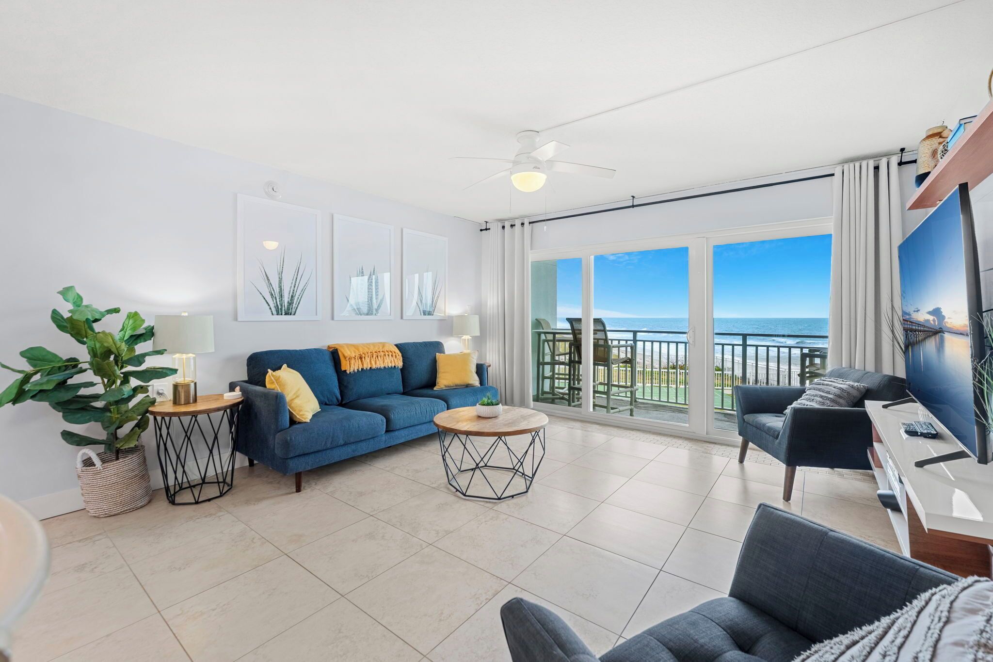 A modern living room with a sofa, coffee table, TV, and a balcony with a view.