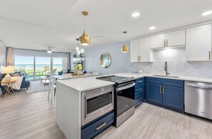 Et moderne køkken med indbyggede hårde hvidevarer, et spiseområde med udsigt og en stor køkkenø.