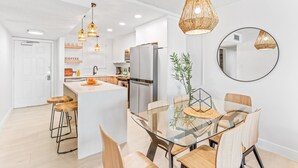 A modern kitchen with white cabinets, stainless steel appliances, and a central island with stools. - Paradise Beach Club - Direct Oceanfront Condos with Heated Pool Pet-Friendly (Satellite Beach)