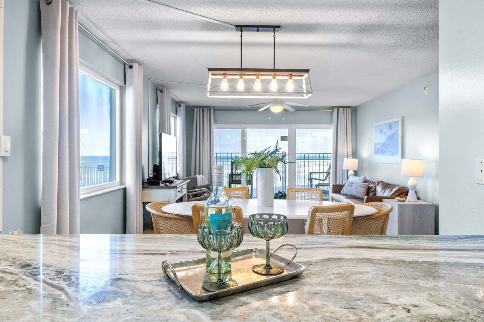 A modern hotel room with a dining area, a balcony with a view, and a ceiling fan.