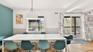 Un'area pranzo moderna con un tavolo bianco, sedie verde acqua e una lampada a sospensione.
