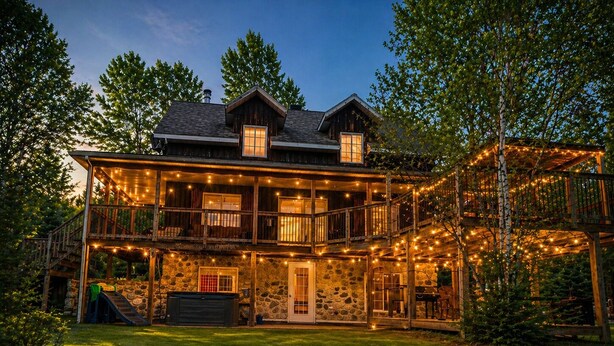 Una casa a due piani con facciata in pietra, un molo di legno e luci decorative.