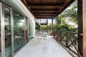 Un espacio al aire libre techado con una mesa y sillas, techo de madera y vistas a follaje.