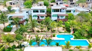 Un complejo residencial de arquitectura moderna, con piscina y palmeras.