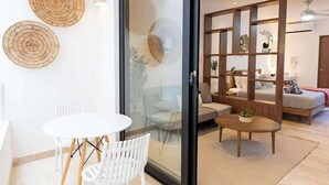 A modern living room with a glass partition, a white dining table, and a wooden coffee table. - Playa Studio: Rooftop Pool, Steps to 5th Avenue (Playa del Carmen)