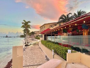 Ein Hotel direkt am Strand mit Poolbar, Palmen und Meerblick.