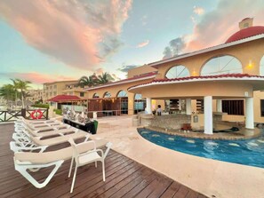 Ein Poolbereich eines Resorts mit Liegestühlen, einem Pool und einem Gebäude mit Rundbogenfenstern.