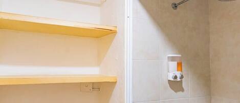 A shower area with a handheld showerhead, a soap dispenser, and a towel rack.