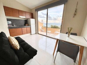 Ein stilvolles Wohnzimmer mit Küche, Essbereich und einer großen Schiebeglastür, die auf einen Balkon mit Aussicht führt.