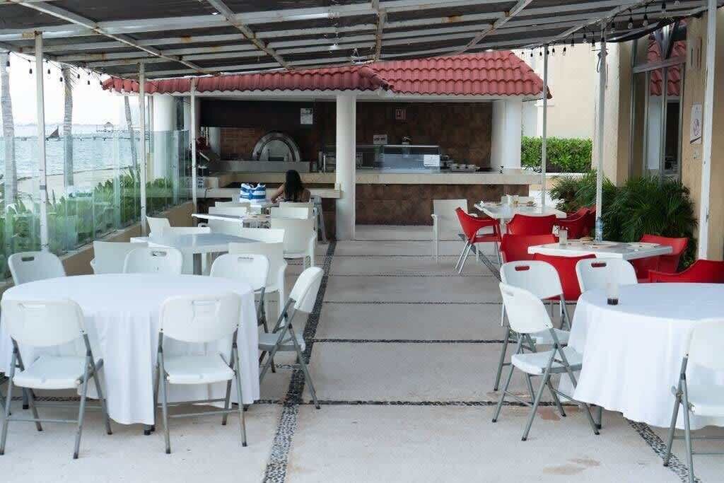 Eine Terrassenanlage im Freien mit Tischen, Stühlen, einer Bar und Blick auf das Meer.