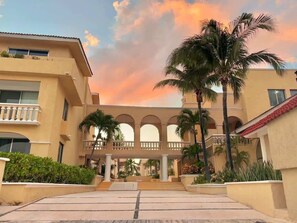 Ein Hotel mit Innenhof, Palmen und Abendhimmel.