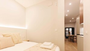 Un dormitorio moderno con una cama grande, una mesita de noche y vistas al comedor.