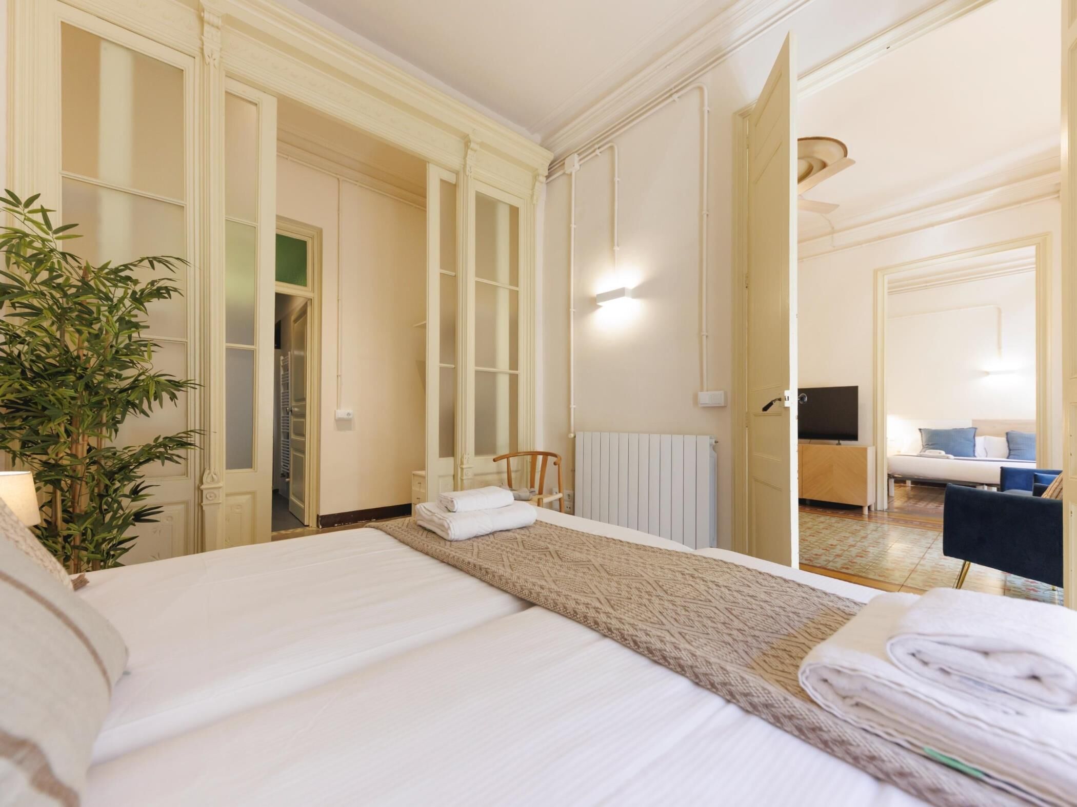 A hotel room with a bed, a radiator, a TV, a desk, and a chair.